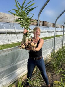 Woman holding large bunch of freshly harvested bunch of vegetables.